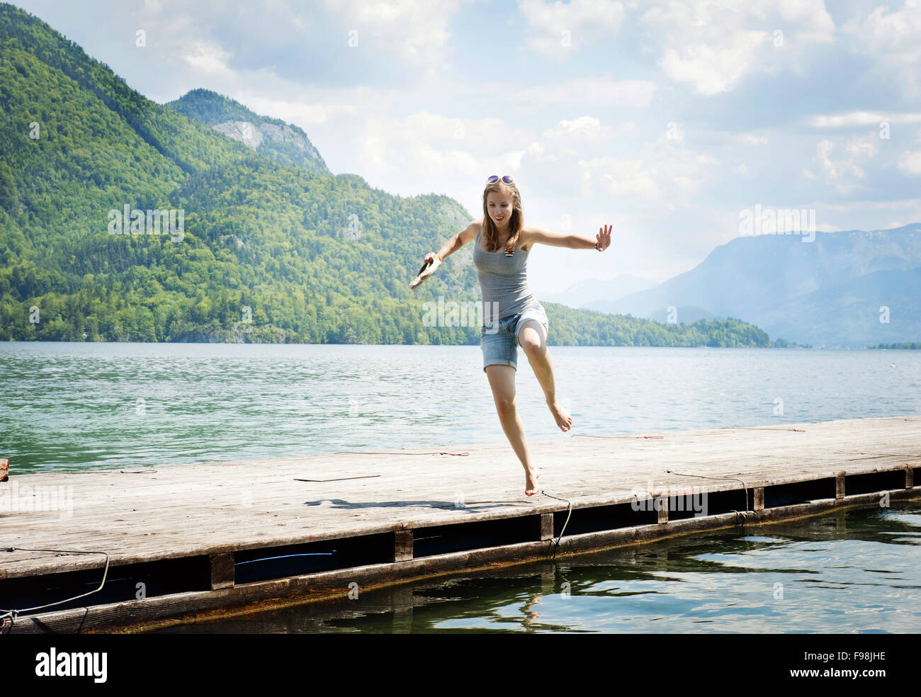 Young woman jumping on the pier by the lake Stock Photo