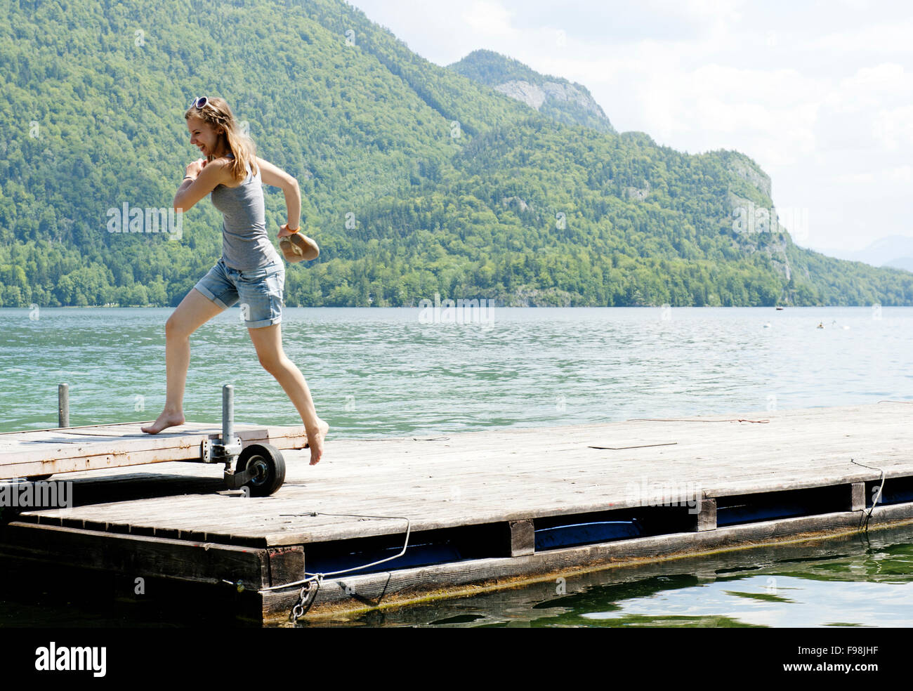 Young woman jumping on the pier by the lake Stock Photo