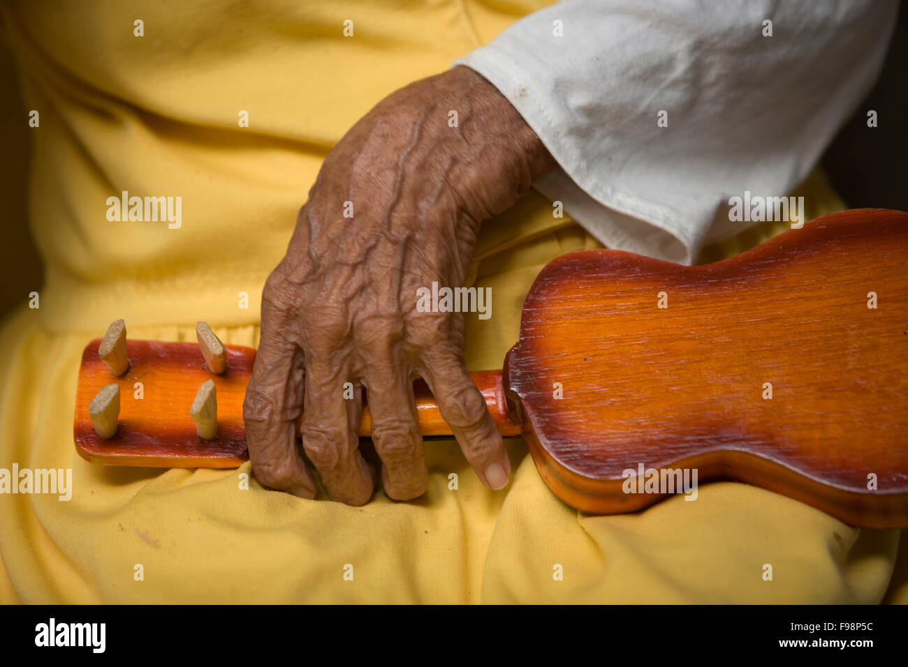 An elderly woman, holds a toy guitar in Our Lady of Guadalupe Home for the Elderly, Mexico City Stock Photo