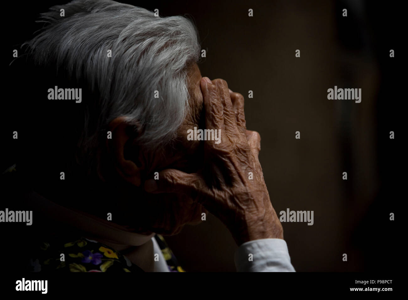 An elderly woman, covers her face from the sunlight in Our Lady of Guadalupe Home for the Elderly, Mexico City Stock Photo