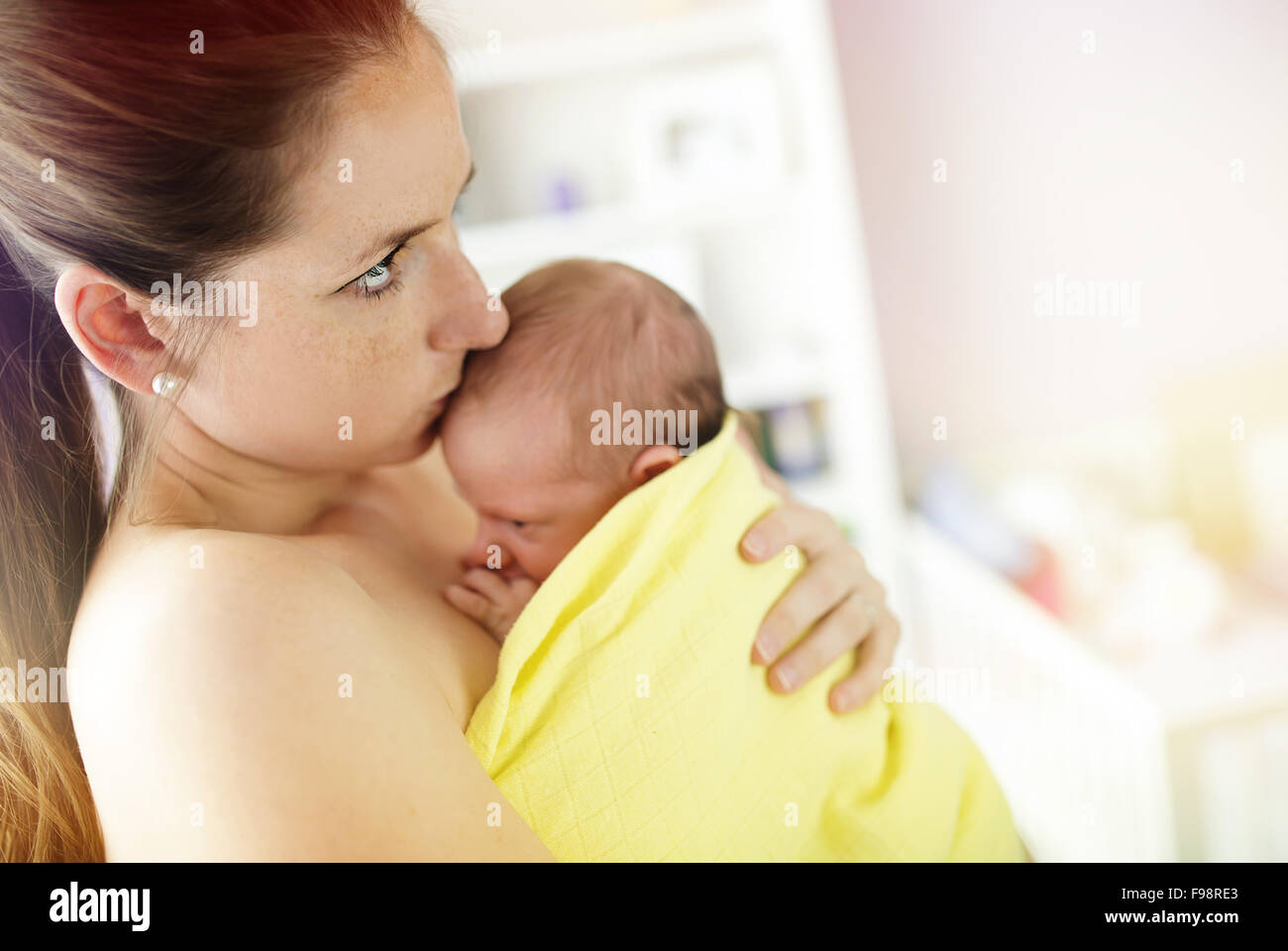 Young mother holding and kissing her newborn baby girl at home Stock Photo