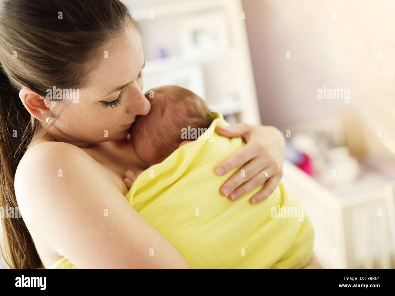Young mother holding and kissing her newborn baby girl at home Stock Photo