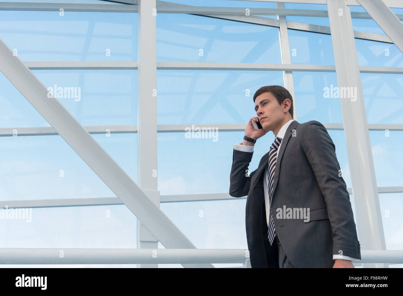 Man on smart phone - young business man in airport. Casual urban professional businessman using smartphone smiling happy inside Stock Photo