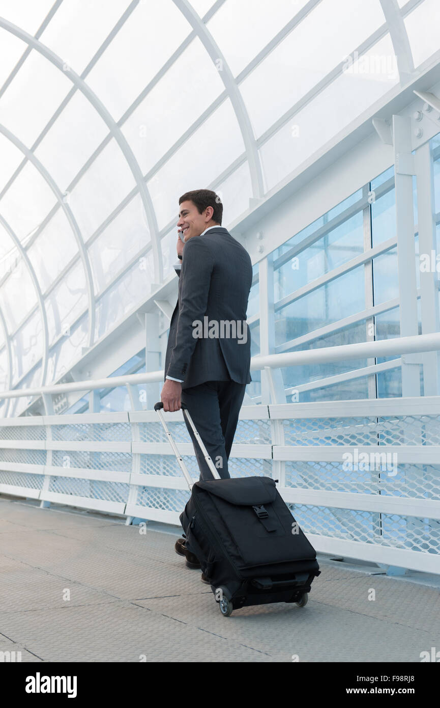 Man on smart phone - young business man in airport. Casual urban professional businessman using smartphone smiling happy inside Stock Photo