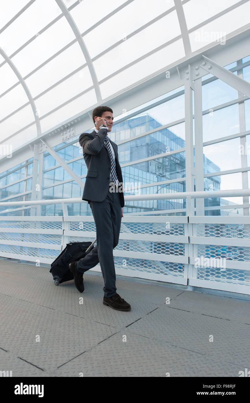 Man on smart phone - young business man in airport. Casual urban professional businessman using smartphone smiling happy inside Stock Photo