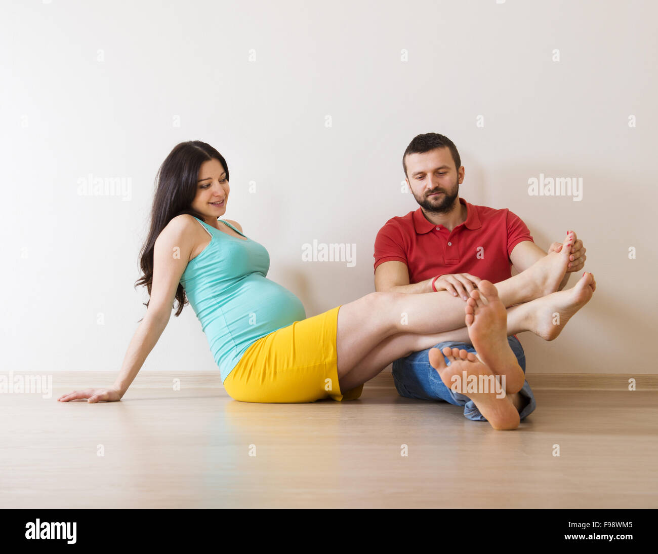 Young couple is sitting on the floor in their empty new house. Woman is