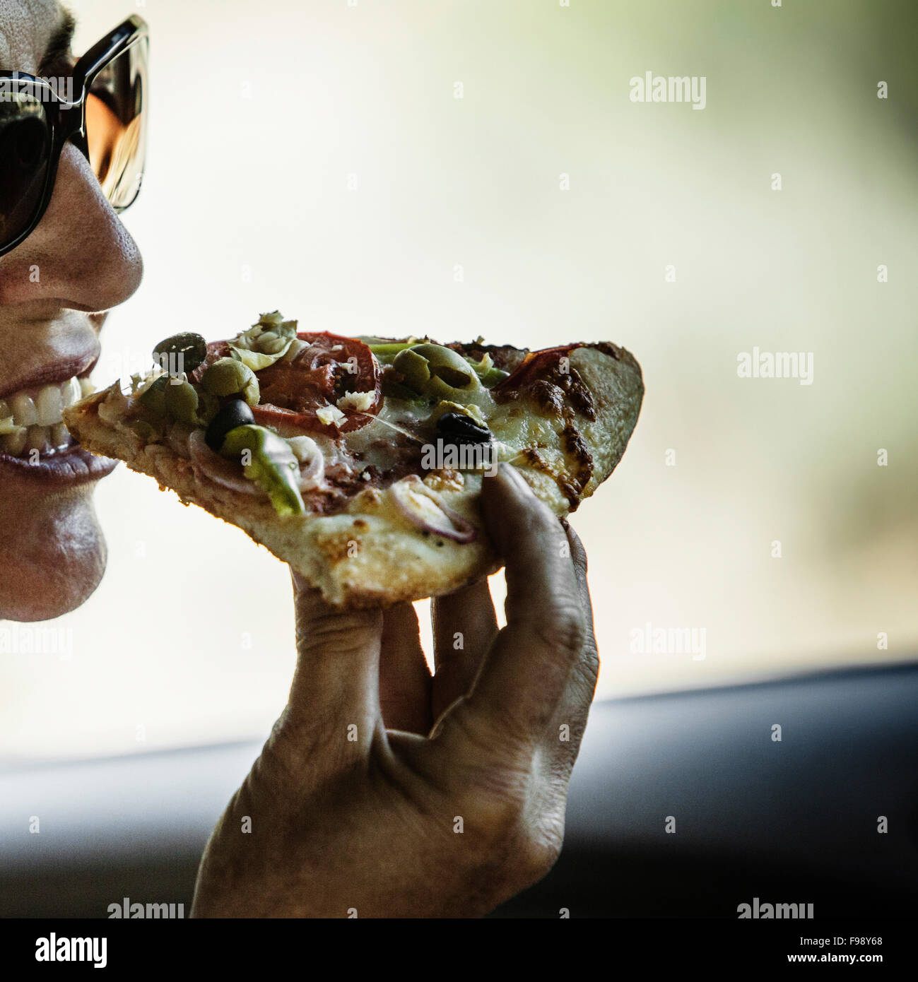 A woman taking a bite of pizza. Stock Photo