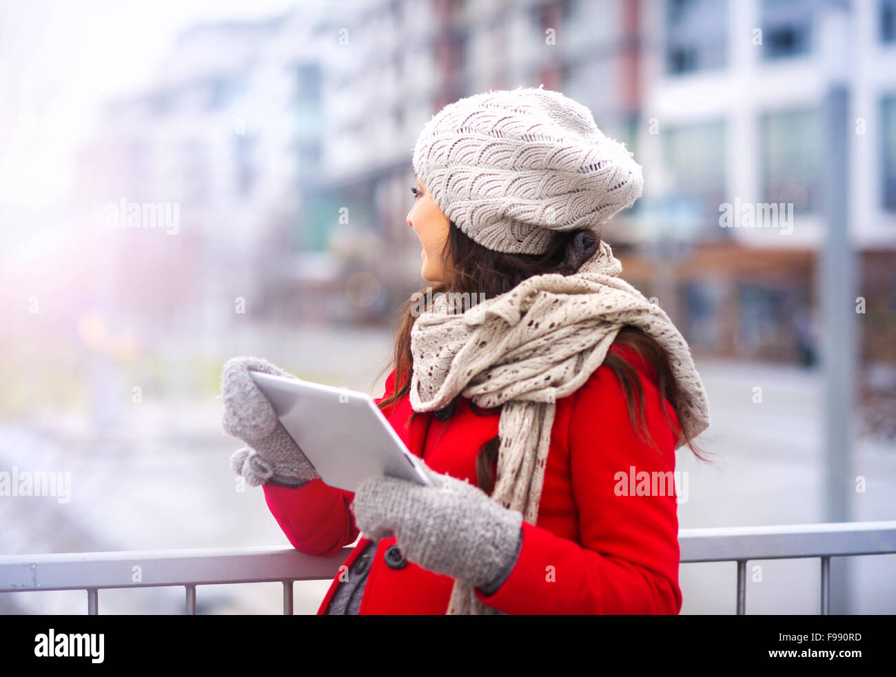 Pregnant woman in knitted clothes holding digital tablet, outside in winter weather Stock Photo