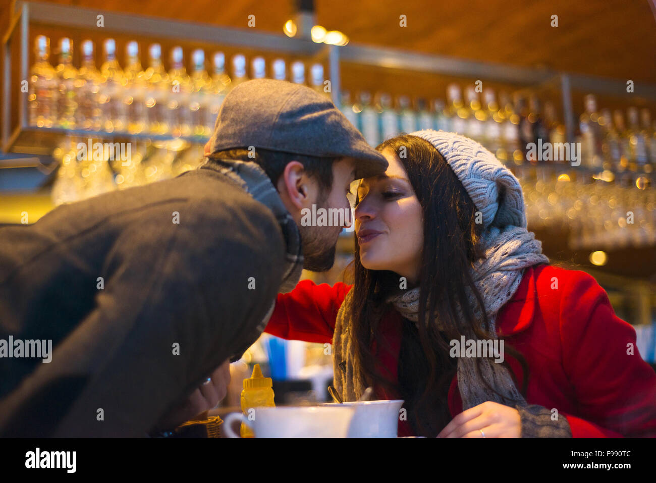 Young couple in winter clothes kissing in cafe Stock Photo