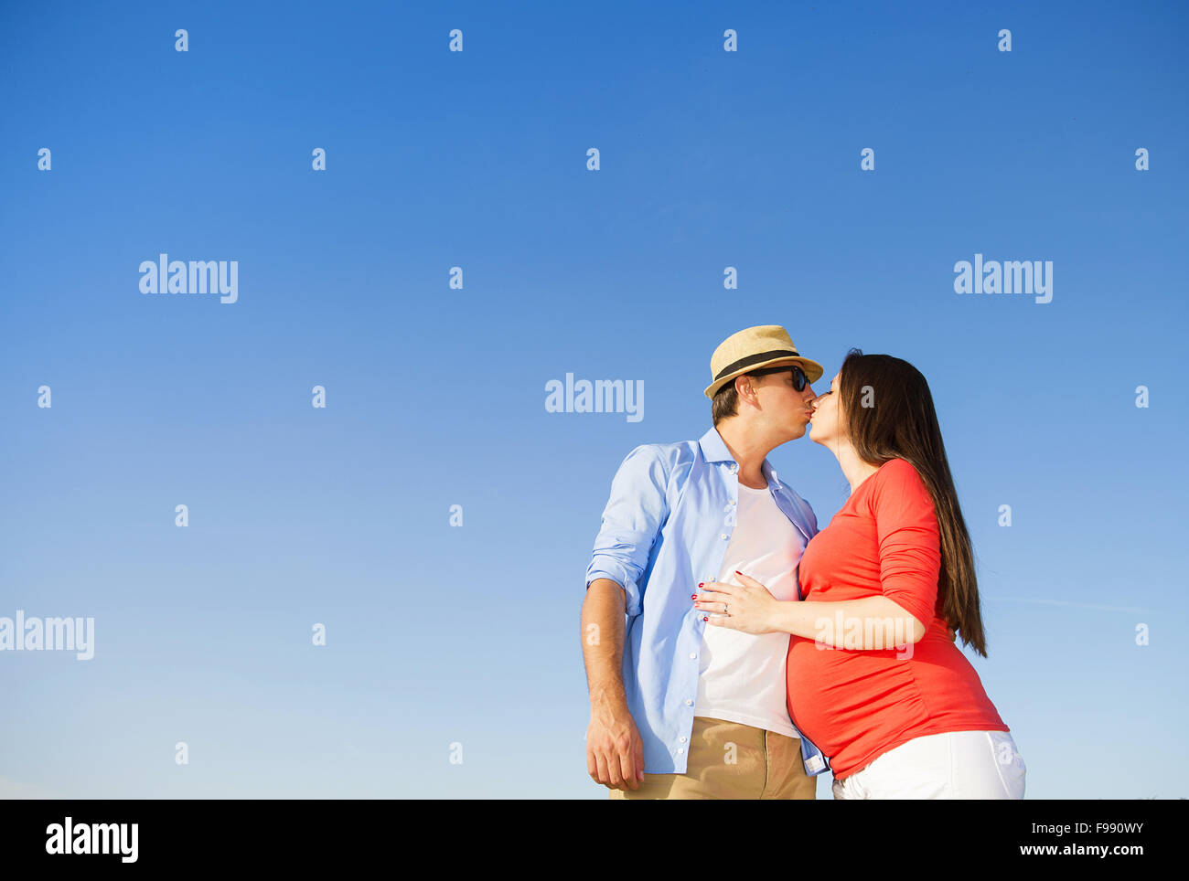 Portrait of young pregnant couple with blue sky Stock Photo - Alamy