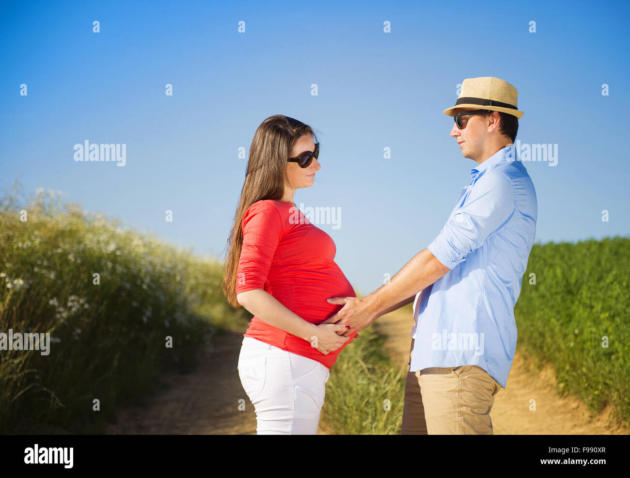 Portrait of young pregnant couple with blue sky Stock Photo - Alamy
