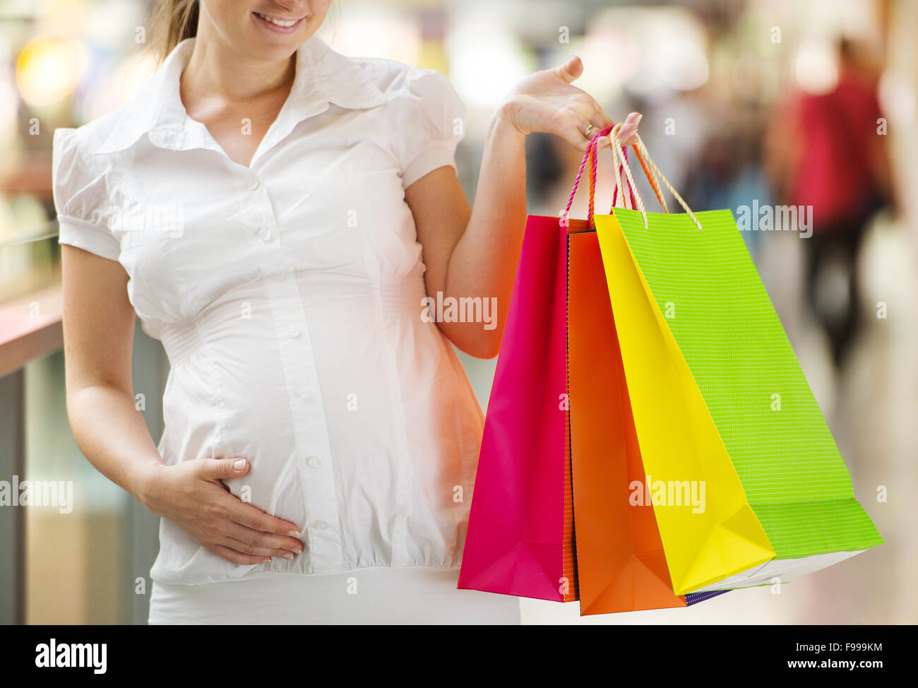 Young pregnant woman with shopping bags in shopping mall Stock Photo