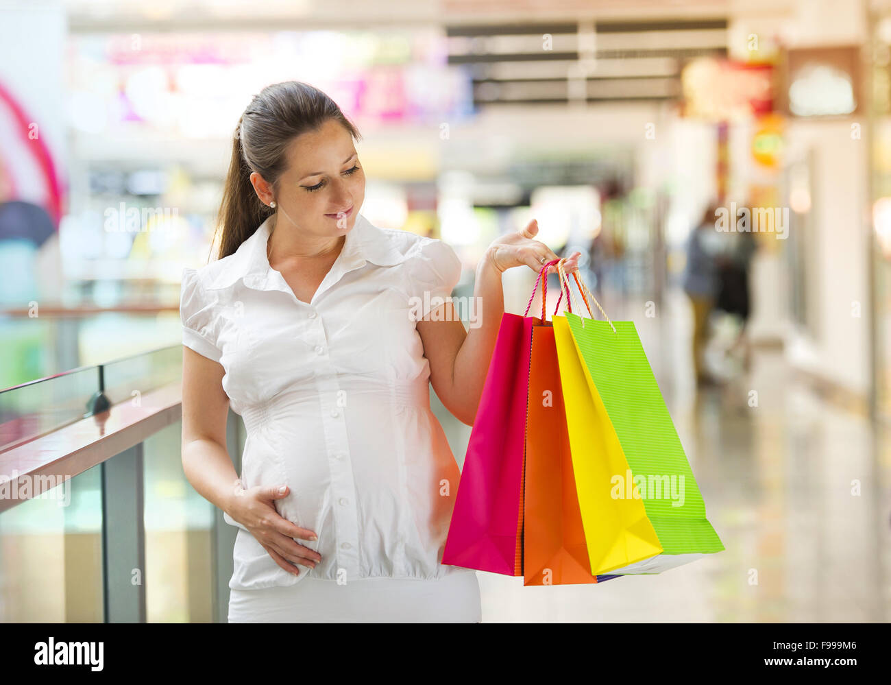 Young pregnant woman with shopping bags in shopping mall Stock Photo