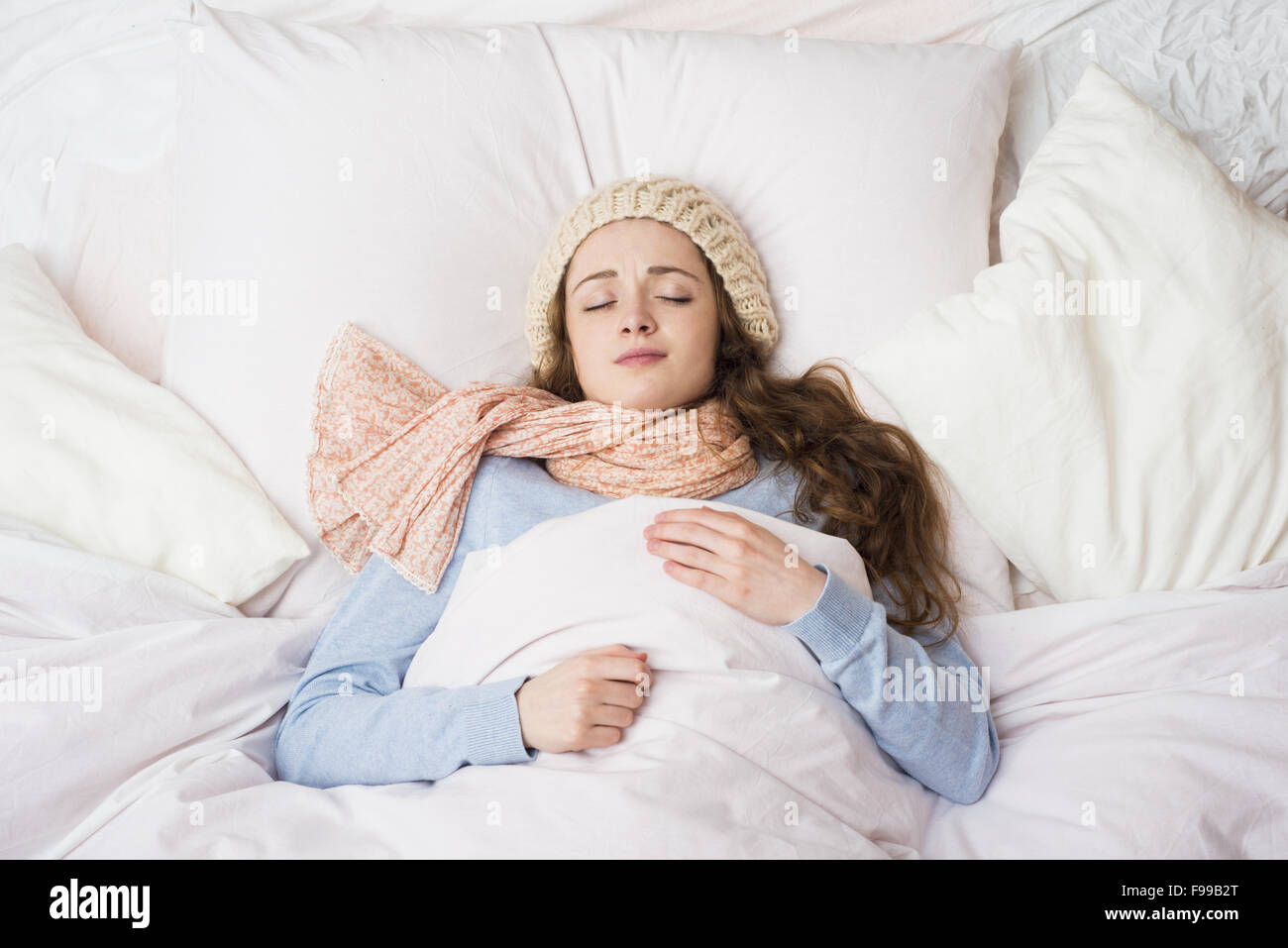 Sick woman lying in bed with high fever. She has cold and flu. Stock Photo