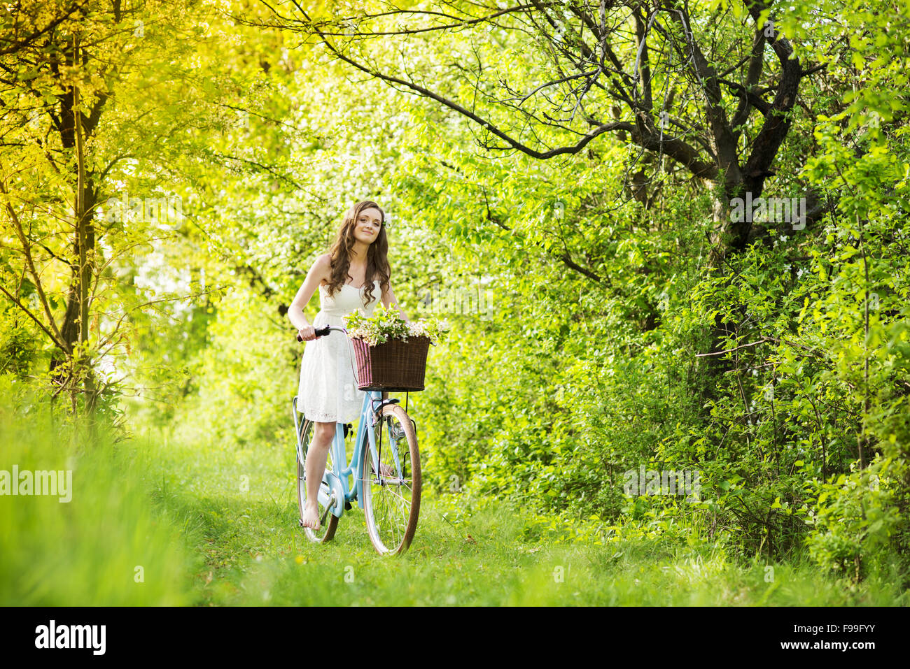 Pretty young woman riding retro bike in green park Stock Photo