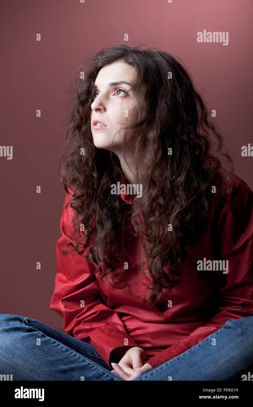girl sitting on the ground on a red background Stock Photo - Alamy