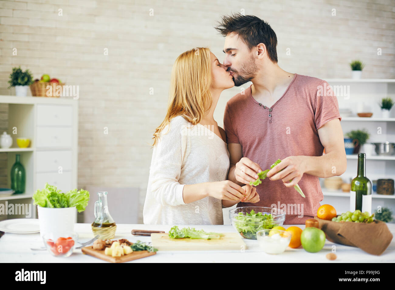 Affectionate young couple kissing while cooking salad Stock Photo Alamy