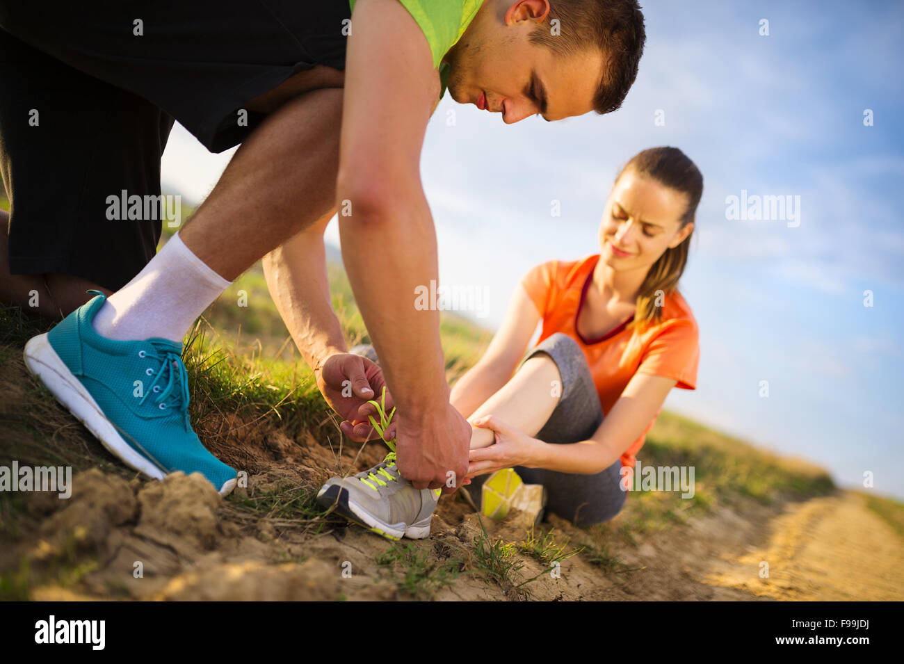 Injury - sports woman with twisted sprained getting help from man touching her ankle. Stock Photo