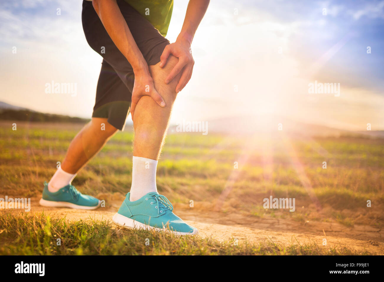 Runner leg and muscle pain during running training outdoors in summer nature Stock Photo