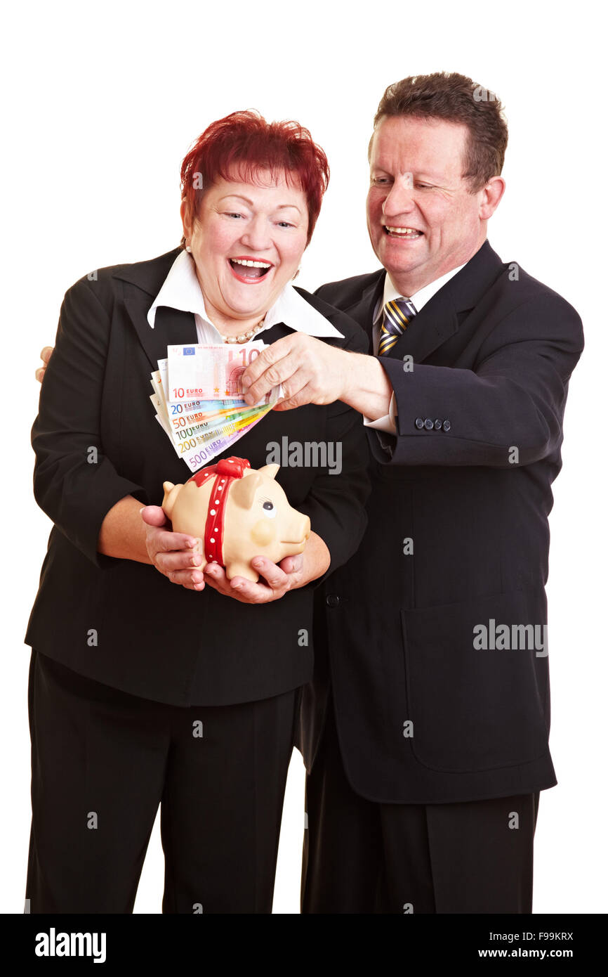 Happy senior couple putting Euro money in a piggy bank Stock Photo - Alamy