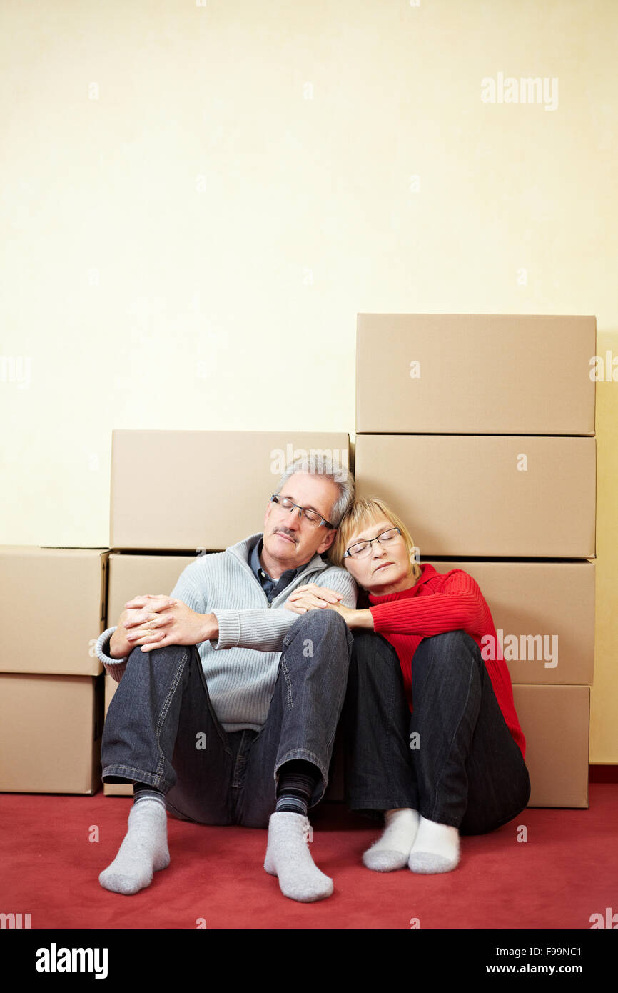 Senior couple sleeping in front of stacked moving boxes Stock Photo