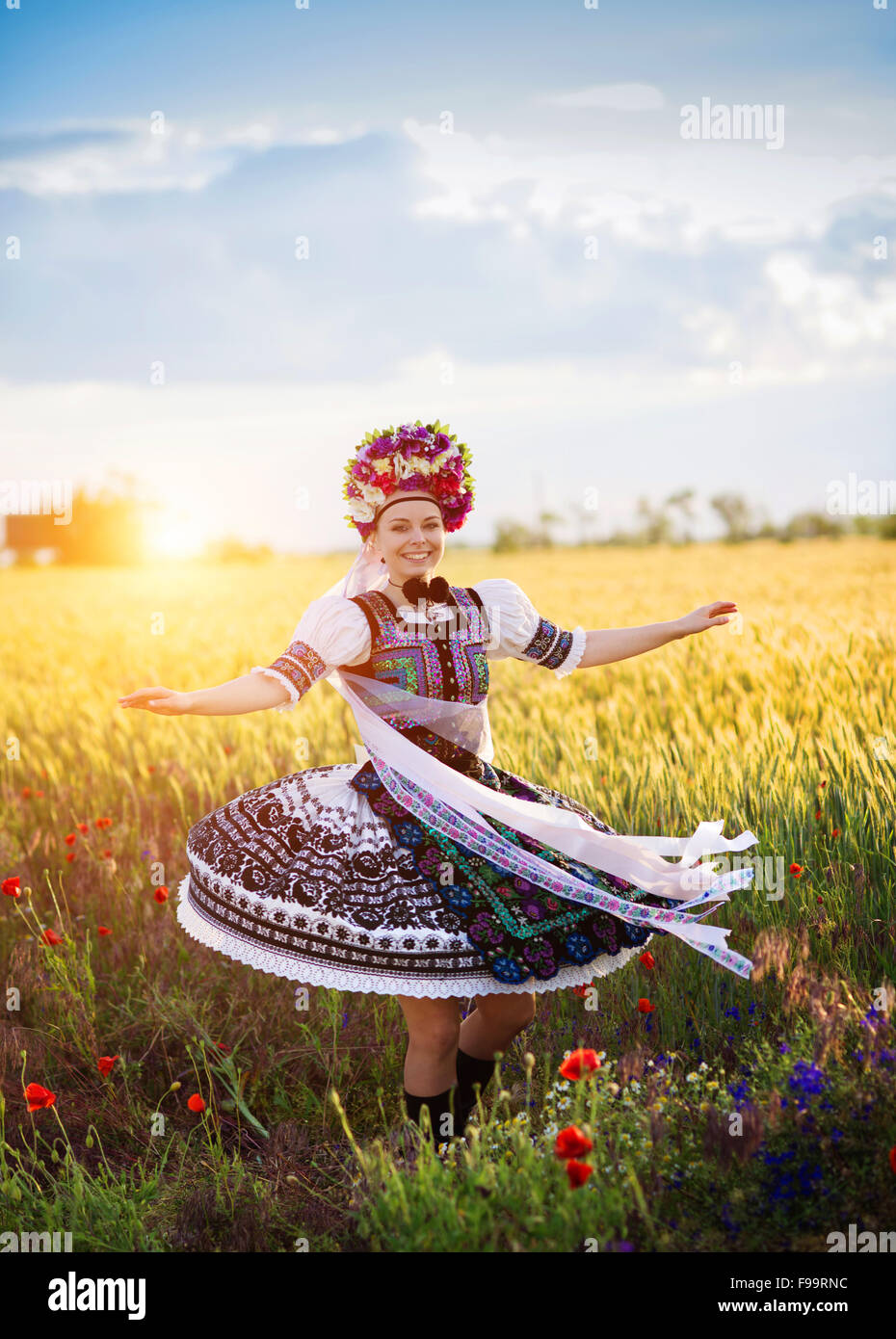 Dancing woman in the field. She is wearing traditional Eastern Europe folk costumes. Stock Photo