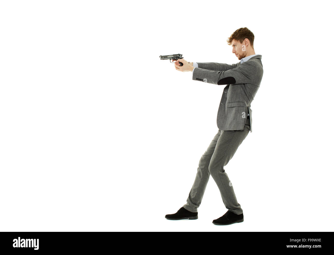 Handsome young man aiming the gun to an invisible target Stock Photo