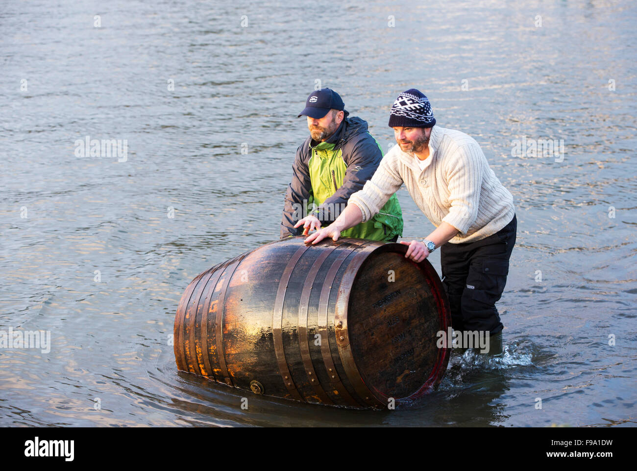Two men recover a beer barrel washed away into Lake Windermere by the floods in Ambleside in the Lake District on Monday 7th Dec Stock Photo