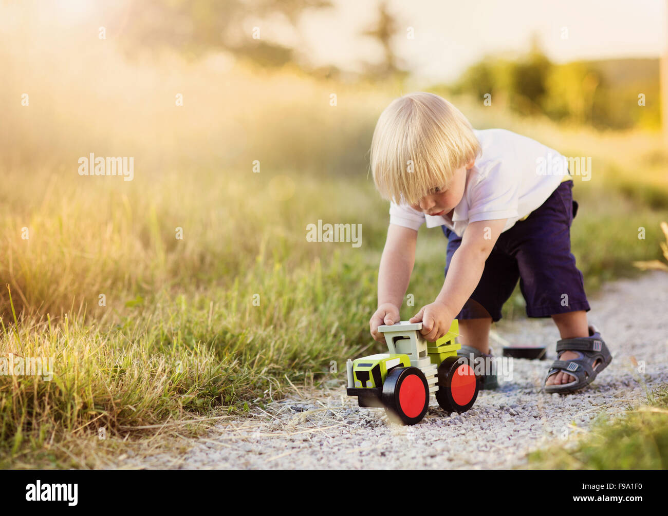 Little boy playing with toy tractor on countryside road Stock Photo Alamy