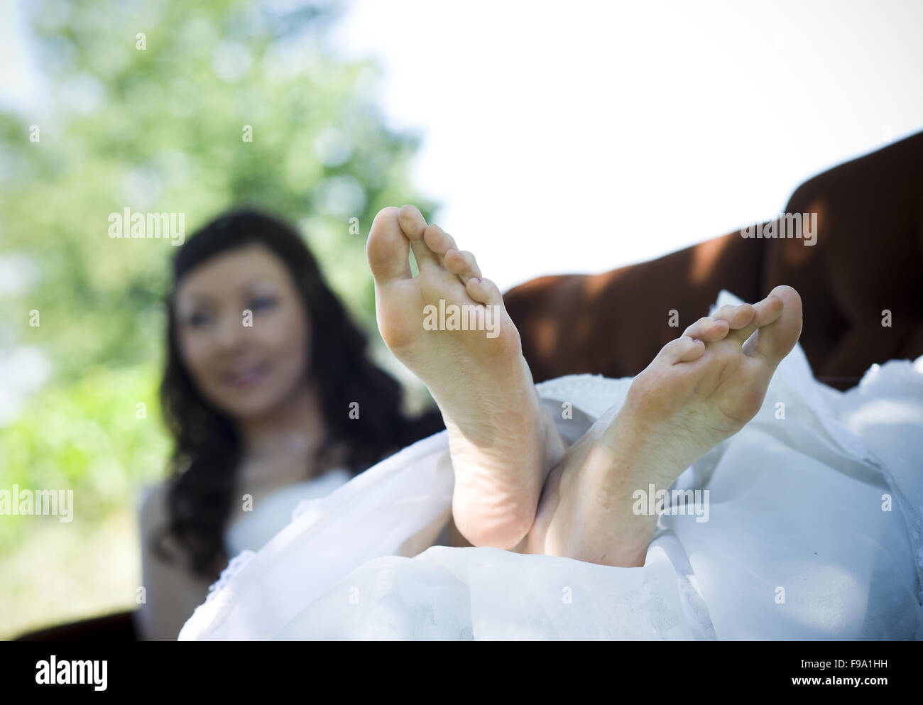 Bride In White Wedding Dress Lying Down At The Meadow Stock Photo