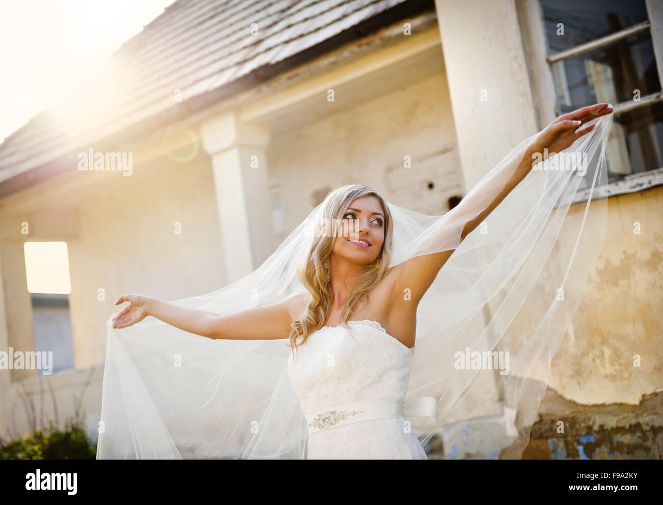 Beautiful young blonde bride with veil posing by old house Stock Photo ...