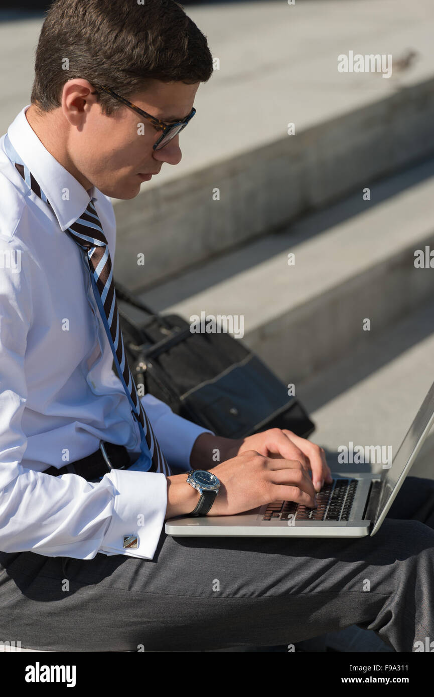 Man with laptop at summer park on bright day Stock Photo