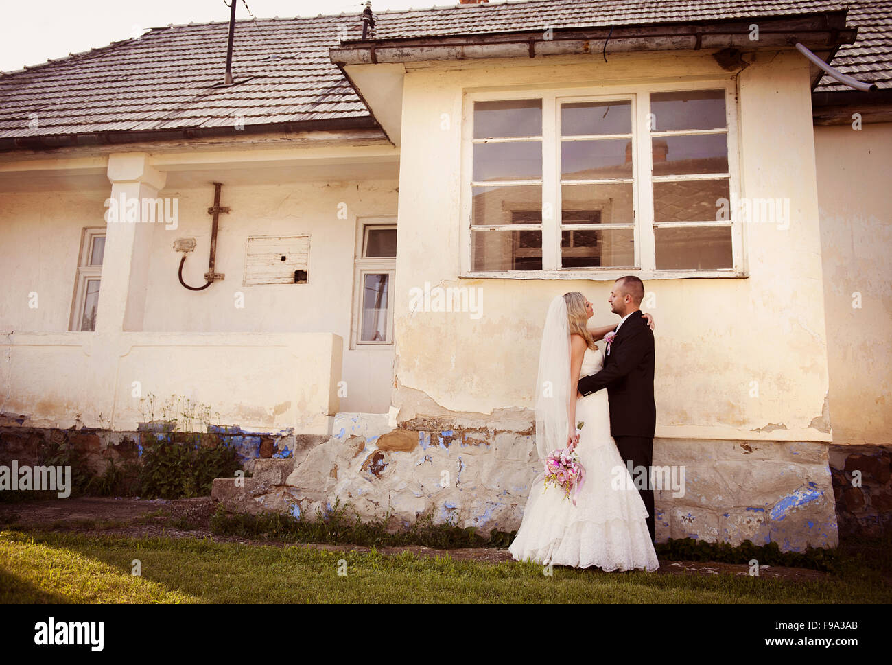 Happy bride and groom posing by the old house Stock Photo - Alamy