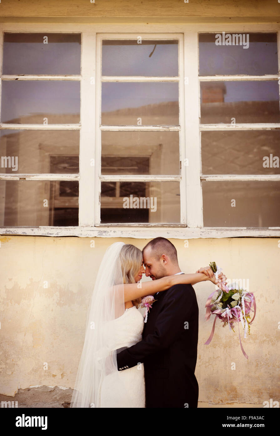 Happy bride and groom posing by the old house Stock Photo - Alamy