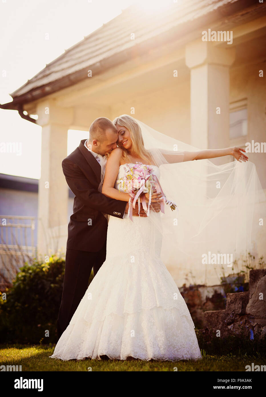 Happy bride and groom posing by the old house Stock Photo - Alamy