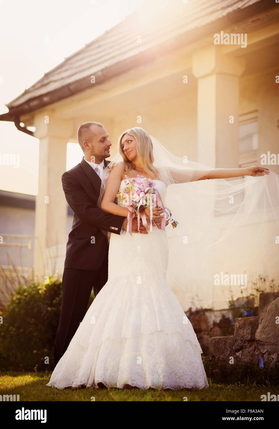 Happy bride and groom posing by the old house Stock Photo - Alamy