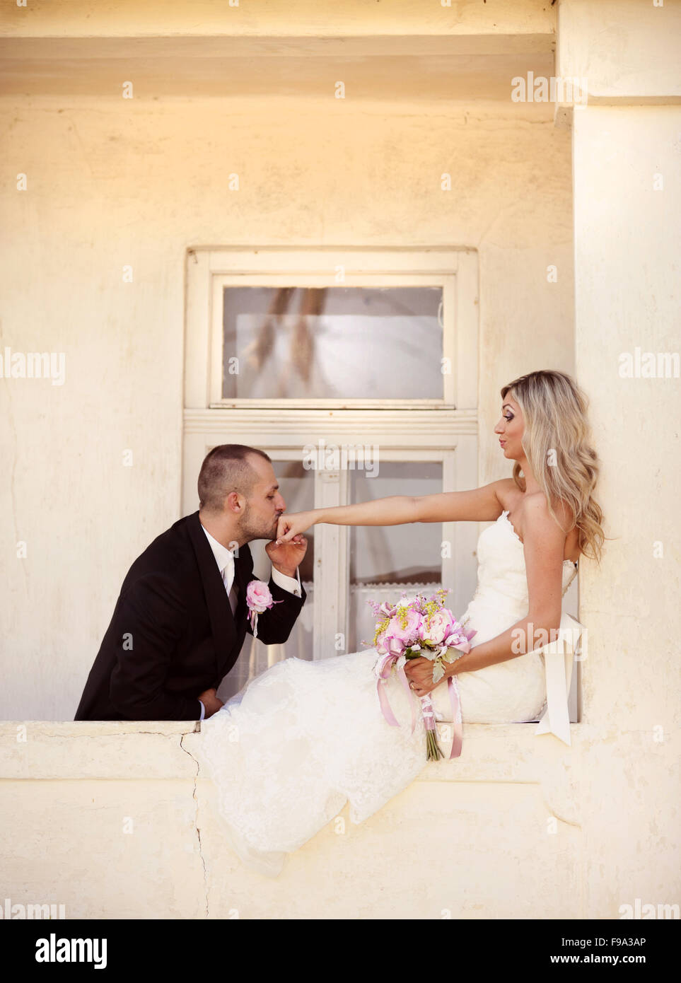 Happy bride and groom posing by the old house Stock Photo - Alamy