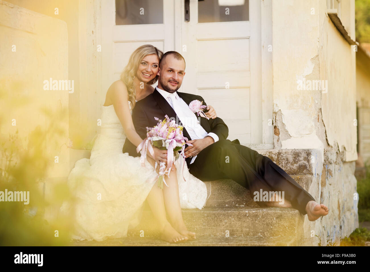 Happy bride and groom posing by the old house Stock Photo - Alamy
