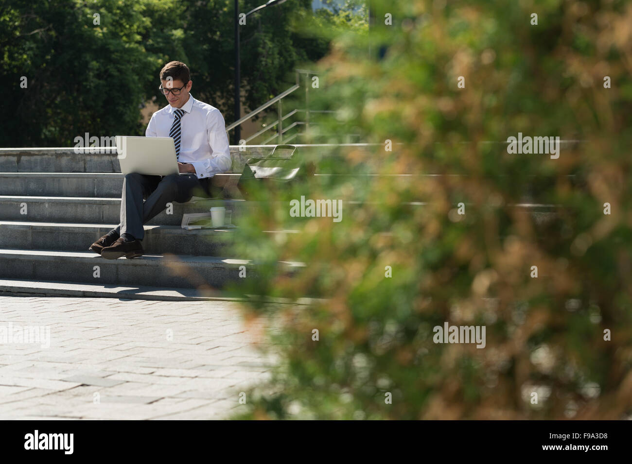 Man with laptop at summer park on bright day Stock Photo