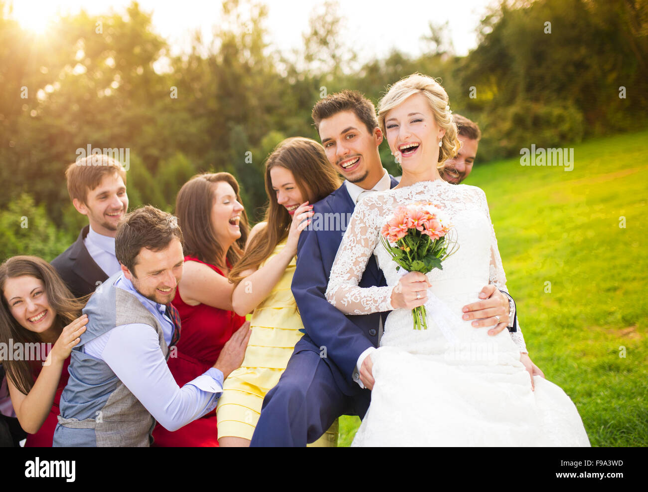 Portrait of newlywed couple having fun with bridesmaids and groomsmen in green sunny park Stock Photo