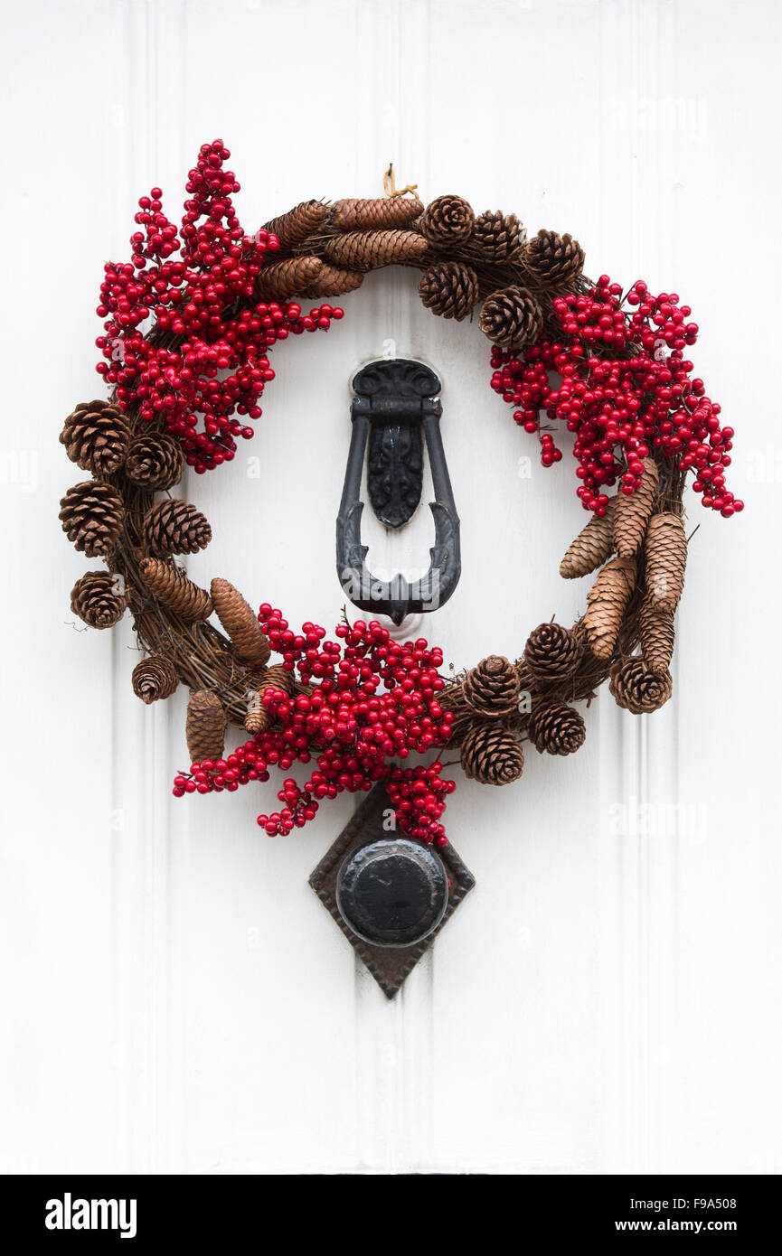 Christmas pine cone and red berry wreath on a white wooden door Stock Photo