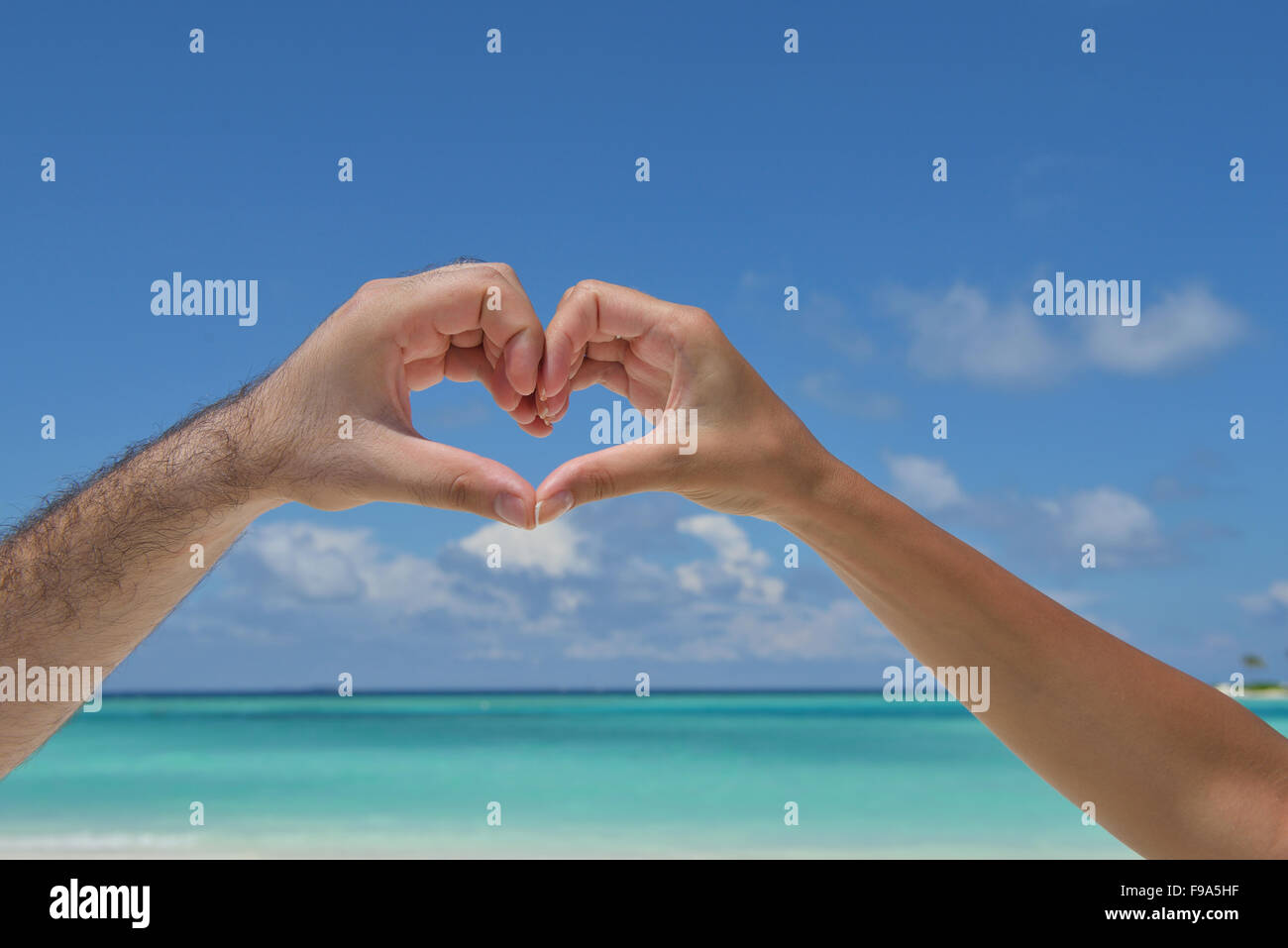romantic couple make heart shape symbol of love with arms on sunny ...