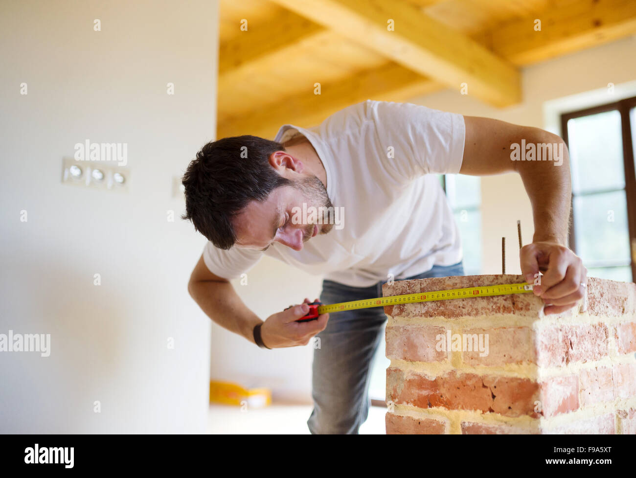 Handyman measuring unfinished room in new house Stock Photo