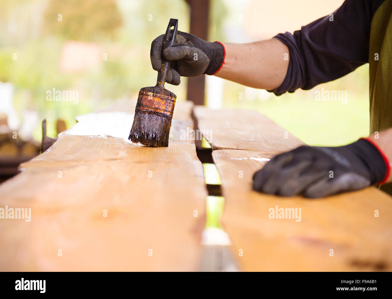 Varnishing of pine wooden planks, workers hand and paintbrush Stock Photo