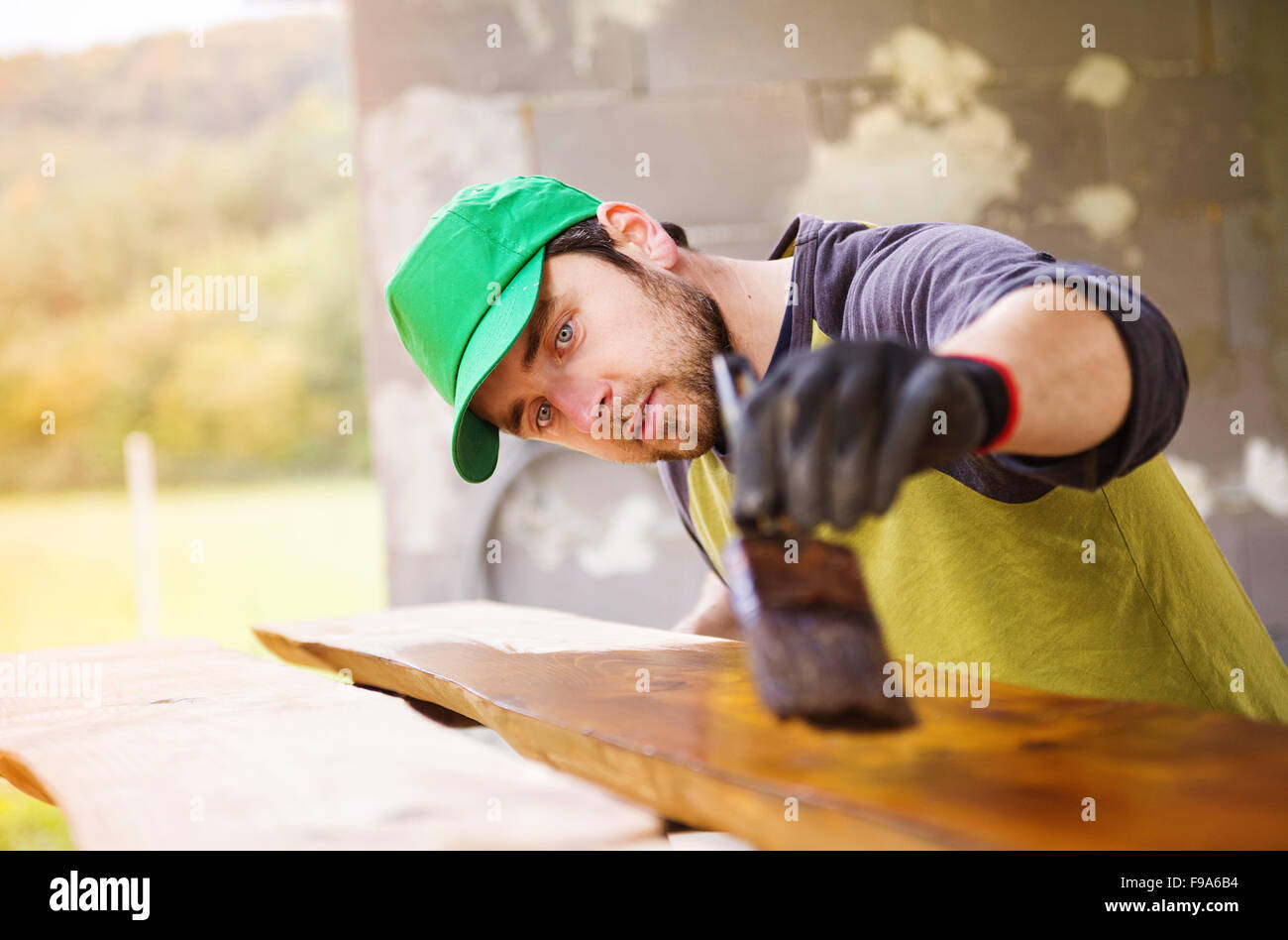 Handyman varnishing pine wooden planks in patio outside the new house Stock Photo