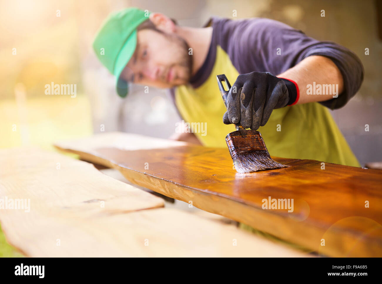 Handyman varnishing pine wooden planks in patio outside the new house Stock Photo