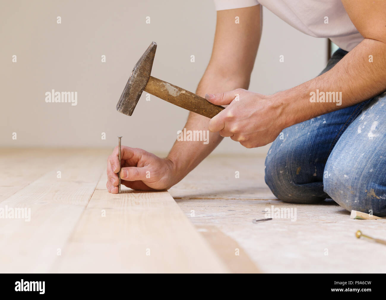 Handyman installing wooden floor in new house Stock Photo