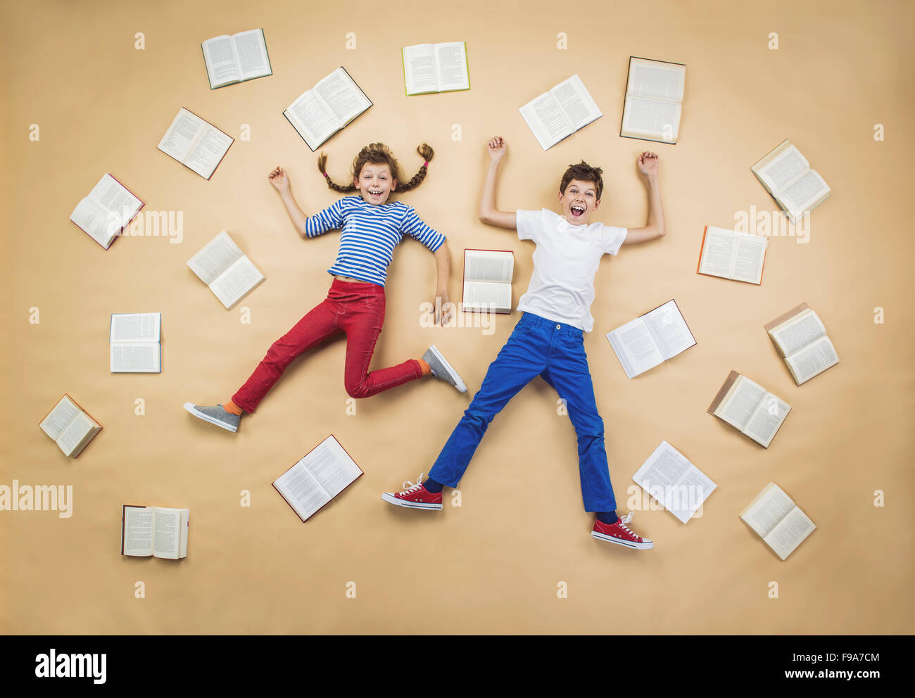 Happy children lying on the floor with group of books Stock Photo