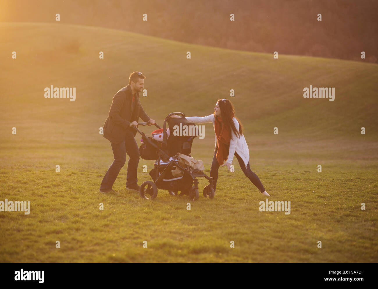 Happy and young family with pram during the walk in nature Stock Photo