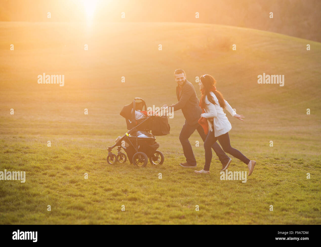 Happy and young family with pram during the walk in nature Stock Photo